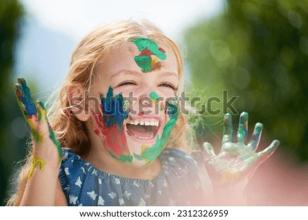 Happy, little girl covered in paint and outdoors with a lens flare. Happiness or creative, playing or art fun and cheerful or excited young child with painting over her face outside in the summer