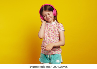 Happy Little Girl Dances And Listens Favourite Track In Headphones, Act Like Dj, Wears Summer Clothes, Closes Eyes With Pleasure, Has Fun Alone