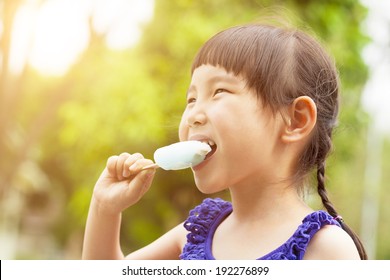 happy little girl eating popsicle at summertime with sunset  - Powered by Shutterstock