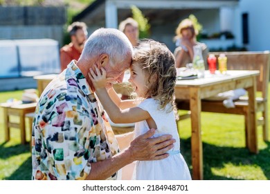 Happy little girl embracing her grandfather at generation family birthday party in summer garden. - Powered by Shutterstock