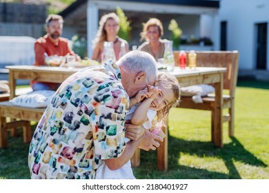 Happy little girl giving birthday present to her senior grandfather at generation family birthday party in summer garden - Powered by Shutterstock