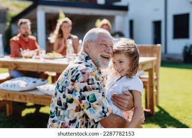 Happy little girl giving birthday present to her senior grandfather at generation family birthday party in summer garden - Powered by Shutterstock