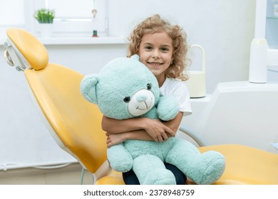 Happy little girl having dentist's appointment in modern clinic. Little patient, adorable little child girl sitting in dentist's chair during appointment in pediatric dentistry clinic - Powered by Shutterstock