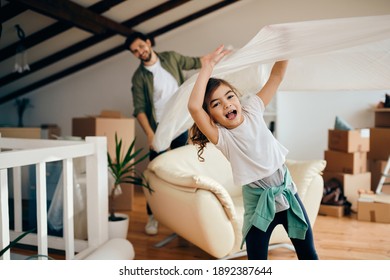 Happy Little Girl Having Fun While Unwrapping Furniture With Her Father At Their New Home. 