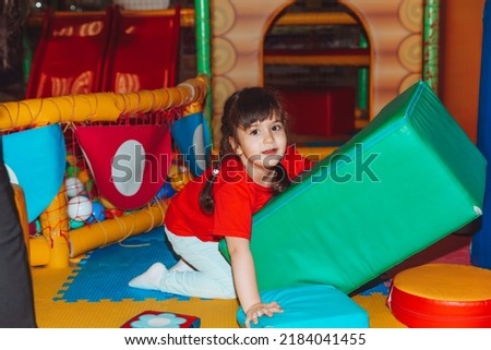 A happy little girl is having fun in an indoor play center. A child plays with colored balls in a pool with a ball on the playground. Foto stock © 