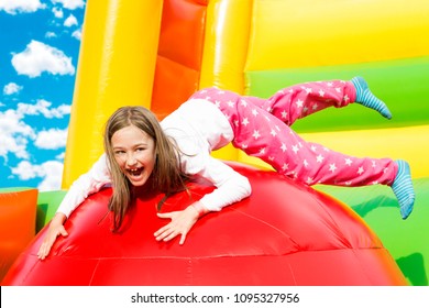 Happy little girl having lots of fun on a inflate castle while jumping.
