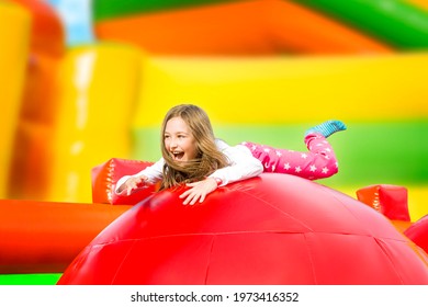 Happy little girl having lots of fun on a inflate castle while jumping. Colorful playground.