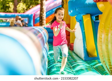 Happy little girl having lots of fun on a jumping castle during sliding. - Shutterstock ID 2153382207