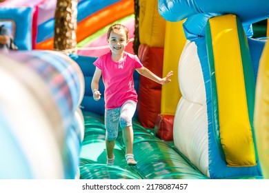 Happy little girl having lots of fun on a jumping castle during sliding. - Powered by Shutterstock