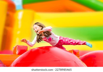 Happy little girl having lots of fun on a inflate castle while jumping. Colorful playground. - Shutterstock ID 2278985465