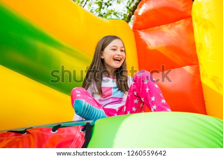 Happy little girl having lots of fun on a jumping castle during sliding.