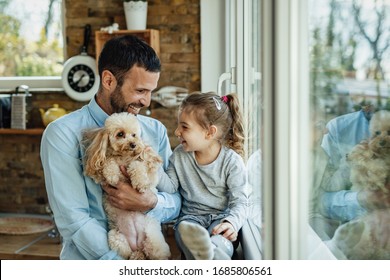 Happy little girl and her father enjoying with their dog at home.  