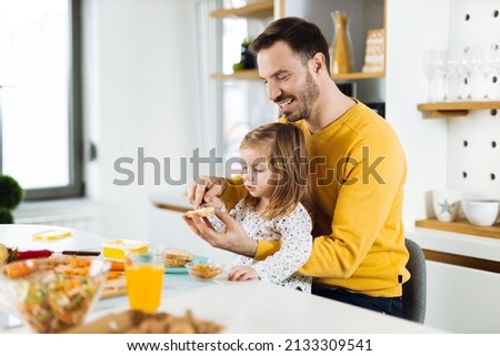 Happy little girl and her father preparing sandwiches  in the kitchen