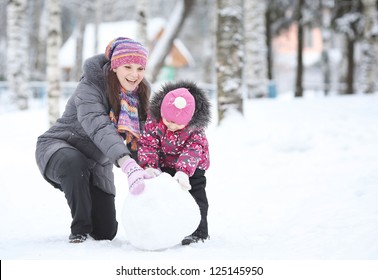 Happy Little Girl With Her Mother Rolled Lumps Of Snow, Make A Snowman