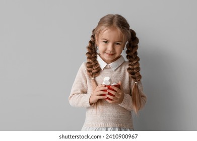 Happy little girl holding cup with marshmallows on grey background - Powered by Shutterstock