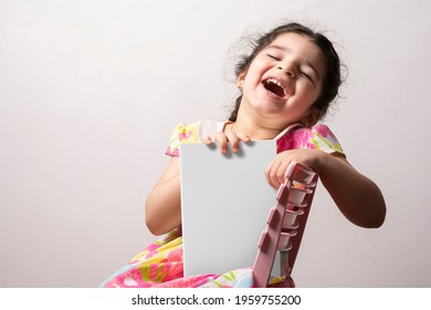 Happy little girl holding a funny story book with blank cover in front of body, editable PSD mock-up series with smart object layers template ready for your design, book cover selection path included.