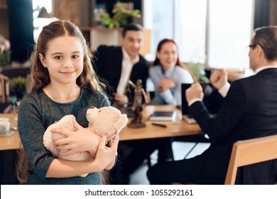 Happy Little Girl Is Hugging Teddy Bear At Office Of Family Lawyer. Registration Of Guardianship. Family In Office Of Family Lawyer.