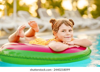 Happy little girl with inflatable toy ring float in swimming pool. Little preschool child learning to swim and dive in outdoor pool of hotel resort. Healthy sport activity and fun for children. - Powered by Shutterstock