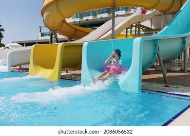 Happy Little Girl Kid Slide Down Hill On Pink Air Mattress In Water Park