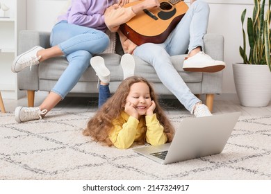 Happy little girl with laptop and her parents resting at home - Shutterstock ID 2147324917
