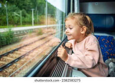 Happy little girl looking out train window outside, while it moving. Traveling by railway, Europe. High quality photo - Powered by Shutterstock