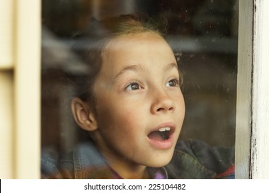 happy little girl looking through an old window