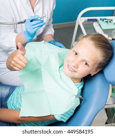 Happy Little Girl With Open Mouth Undergoing Dental Treatment At Clinic. Dentist Checked And Curing Teeth A Child Patient In The Dental Office