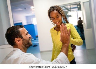 Happy Little Girl And Paediatrician Doing High Five After Medical Checkup In Hospital