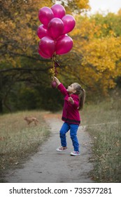 Happy little girl playing with air balloons in forest at the autumn day