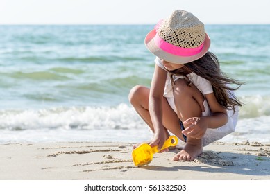Schönes kleines Mädchen, das am Strand spielt
