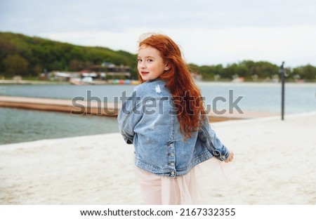 Happy little girl with red hair runs along the beach. child on the beach