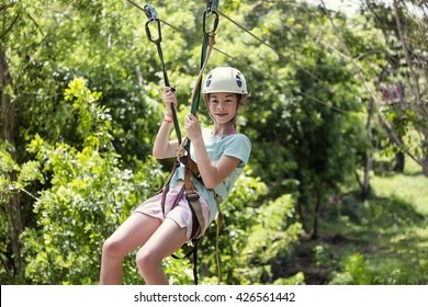 Happy Little Girl Riding A Zip Line In A Lush Tropical Forest 