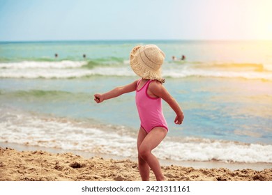 Happy little girl runs on the beach in summer back to camera. The kid in straw hat - Powered by Shutterstock