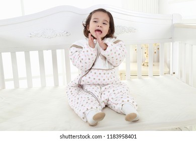 Portrait Of Happy Little Girl Sitting On Bed With Legs Crossed Kid