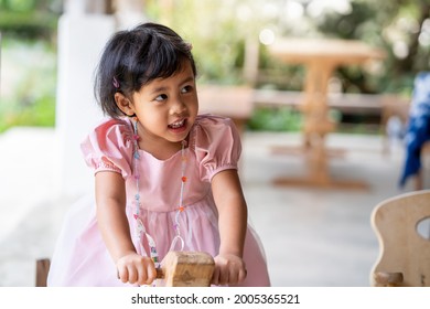 Happy Little Girl Sitting On Wooden Chair Outdoor.