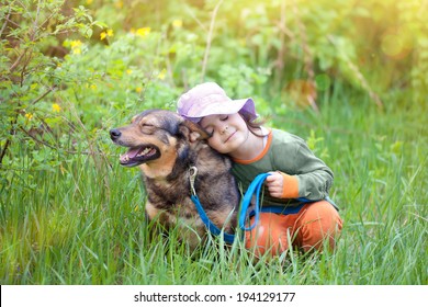 Happy Little Girl Sleeping With Dog On The Grass