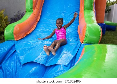 Happy little girl sliding down an inflatable bounce house