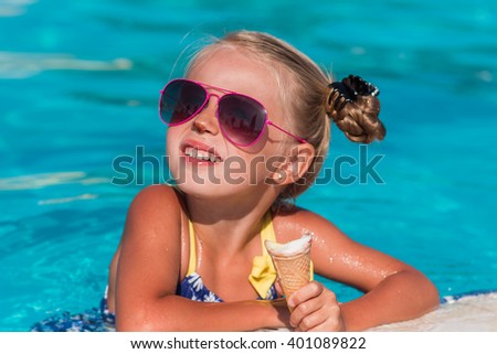 happy little girl in sunglasses eating ice cream in the pool
