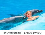 Happy little girl swimming with dolphins. Swimming, bathing and communication with dolphins.