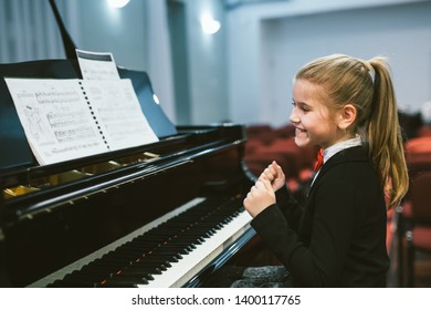 happy little girl teaching to play piano in music school - Powered by Shutterstock