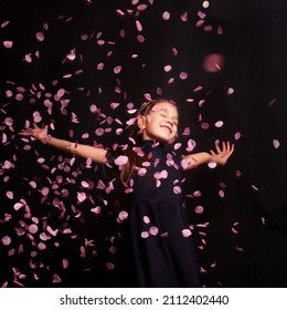 
Happy Little Girl Throwing Confetti On A Black Background