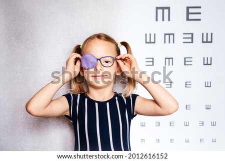 Happy little girl wearing glasses and eye patch or occluder, amblyopia (lazy eye) treatment