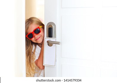 Happy Little Girl Wearing Sunglasses In Hotel Room Opening The Door. Family Vacation Concept