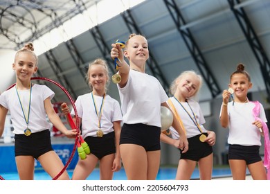 Happy little girls, female gymnastics athletes showing their medals at camera at sports gym, indoors. Concept of win, sport, studying, achievements and success. Teamwork, friendship and support - Powered by Shutterstock