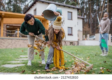 Happy little girls with grandmother picking up leaves and putting them in bucket in garden in autumn - Powered by Shutterstock