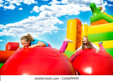 Happy little girls having lots of fun while jumping from ball to ball on an inflate castle.