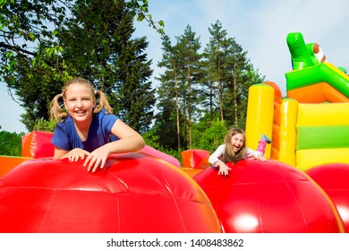 Happy little girls having lots of fun while jumping from ball to ball on an inflate house.