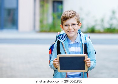 Happy little kid boy with backpack or satchel and glasses. Schoolkid on the way to school. Healthy adorable child outdoors On desk Last day third grade in German. School's out