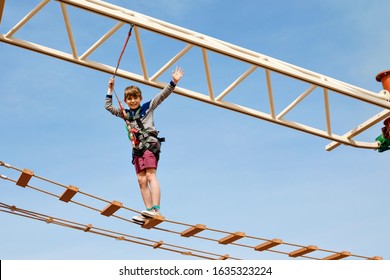 Happy Little Kid Boy Climbing On High Rope Course Trail. Active Child Making Adventure And Action On Family Vacations. Challenge For Brave Kids.