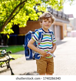 Happy Little Kid Boy With Glasses And Backpack Or Satchel On His First Day To School Or Nursery. Child Outdoors On Warm Sunny Day, Back To School Concept.